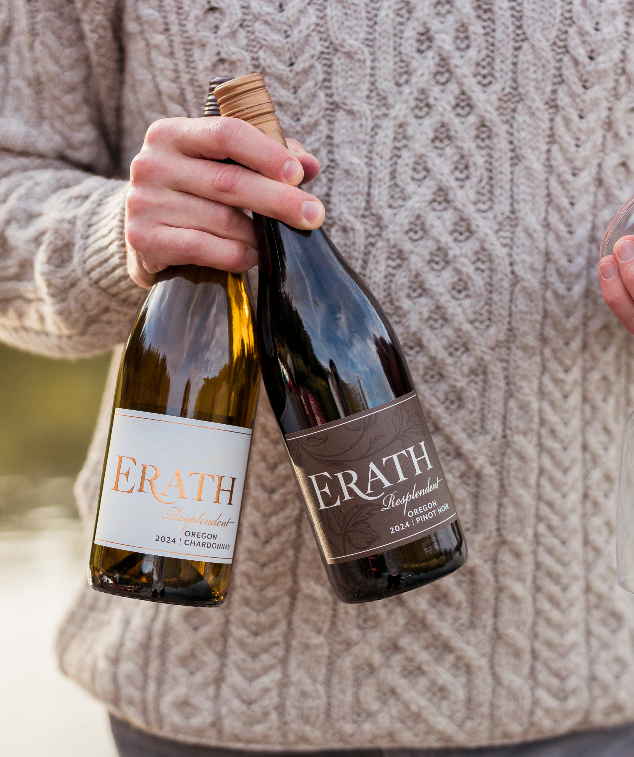 A man holds a bottle each of the 2024 Erath Resplendent Pinot Noir and 2024 Erath Resplendent Chardonnay