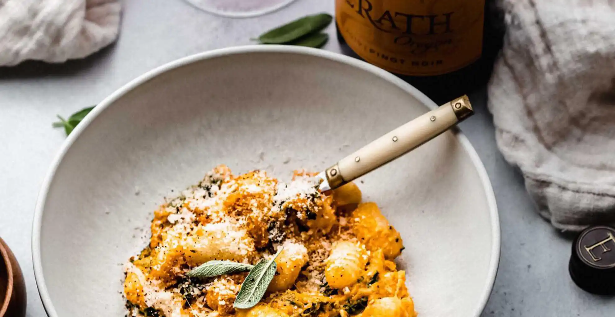 baked gnocchi pumpkin kale in bowl next to erath oregon pinot noir bottle