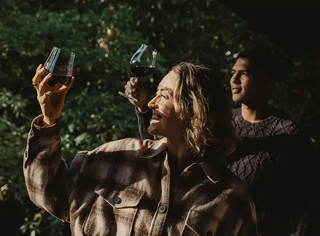 two people raising their wine glasses to the light.