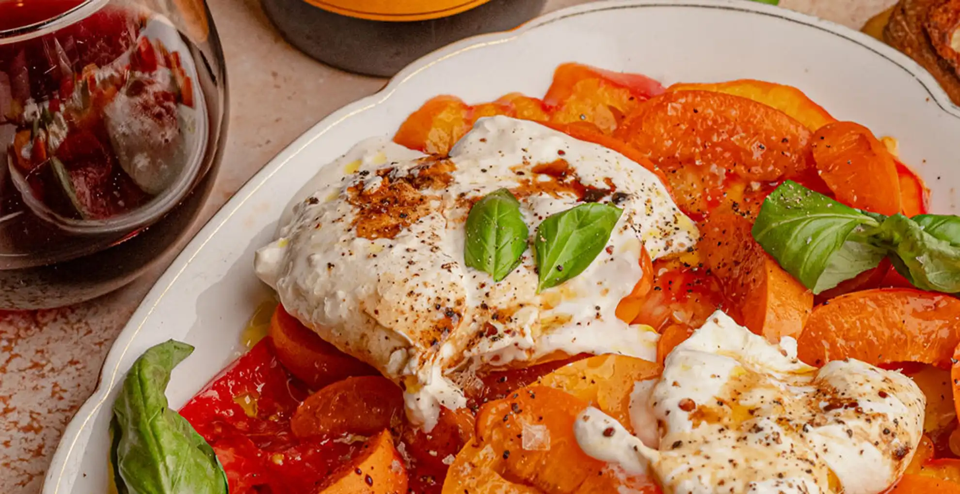 Tomato and Apricot Salad with Burrata on plate with glass of wine