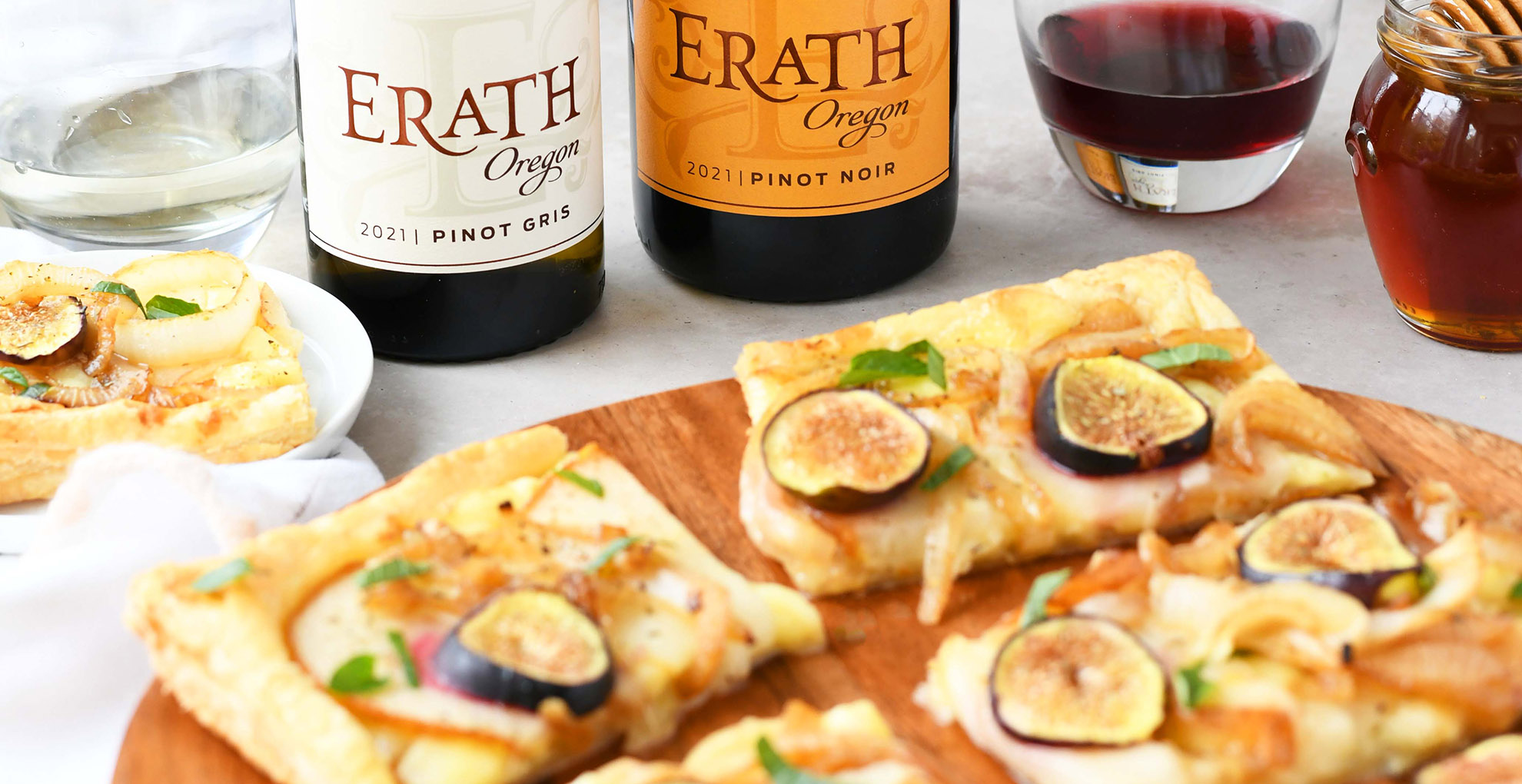 caramelized onion puff pastry with bottles of pinot gris and pinot noir with two glasses of wine