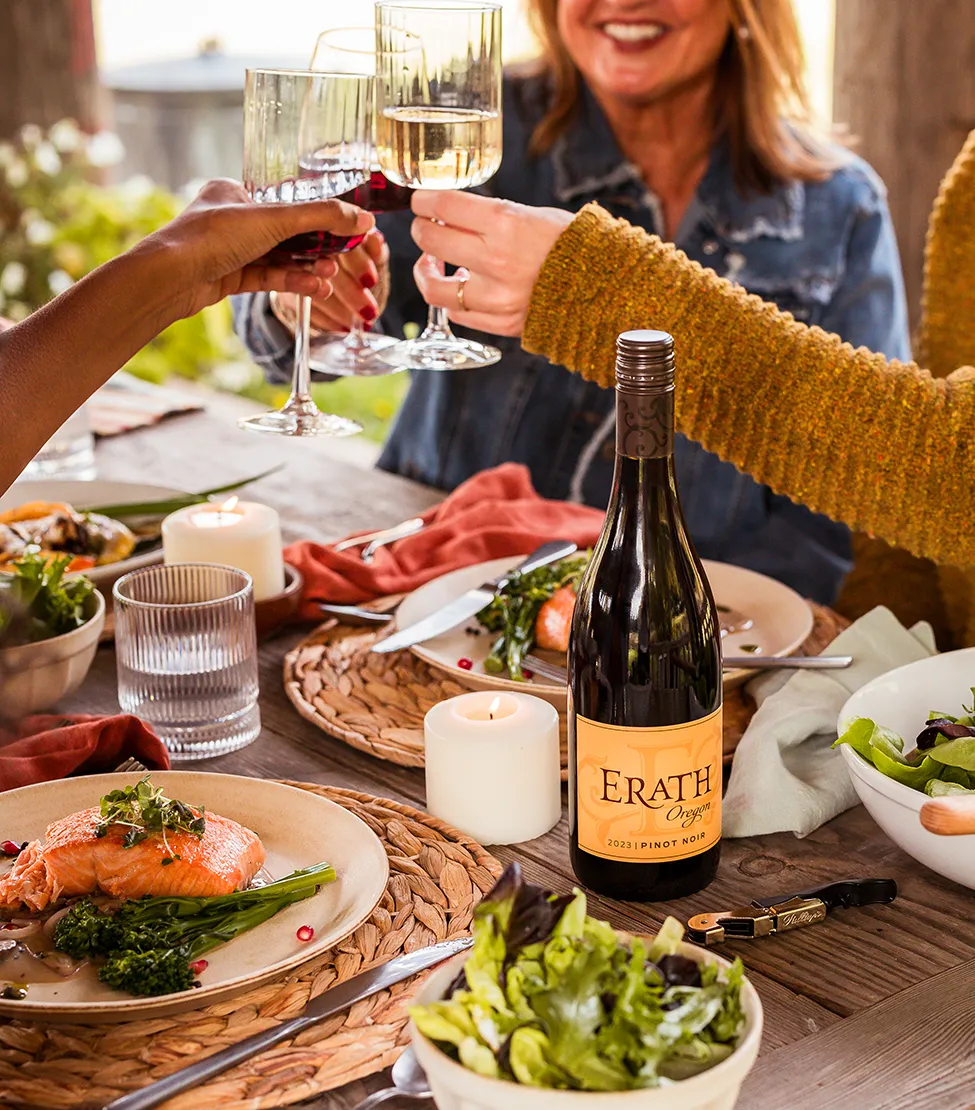 A group of friends gathered around a dinner table raising their glasses of Erath wine.
