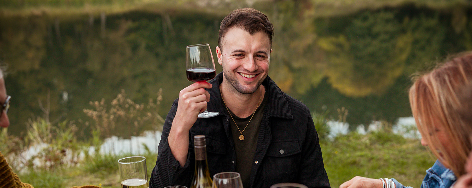 man holding glass of erath oregon pinot noir sitting at dinner table with friends