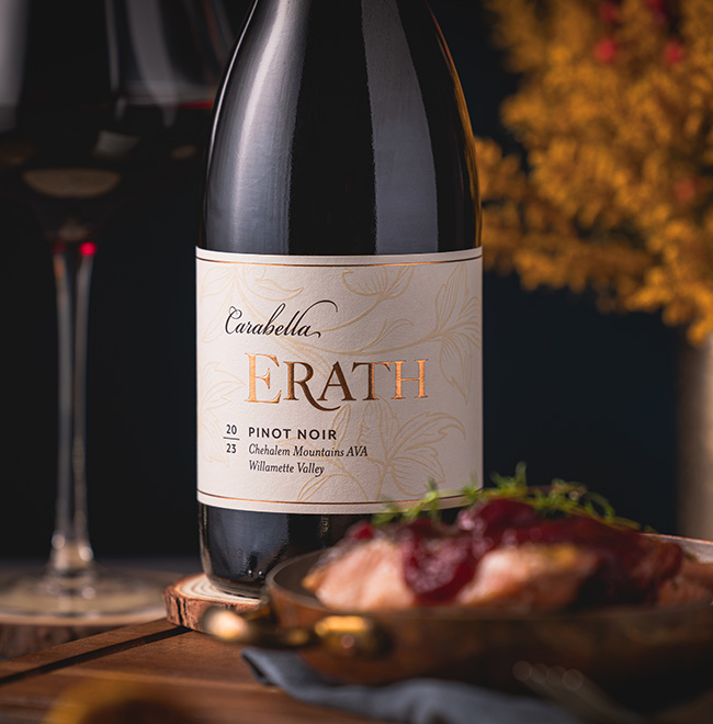 2023 erath carabella pinot noir on table with meat dish with a glass of wine