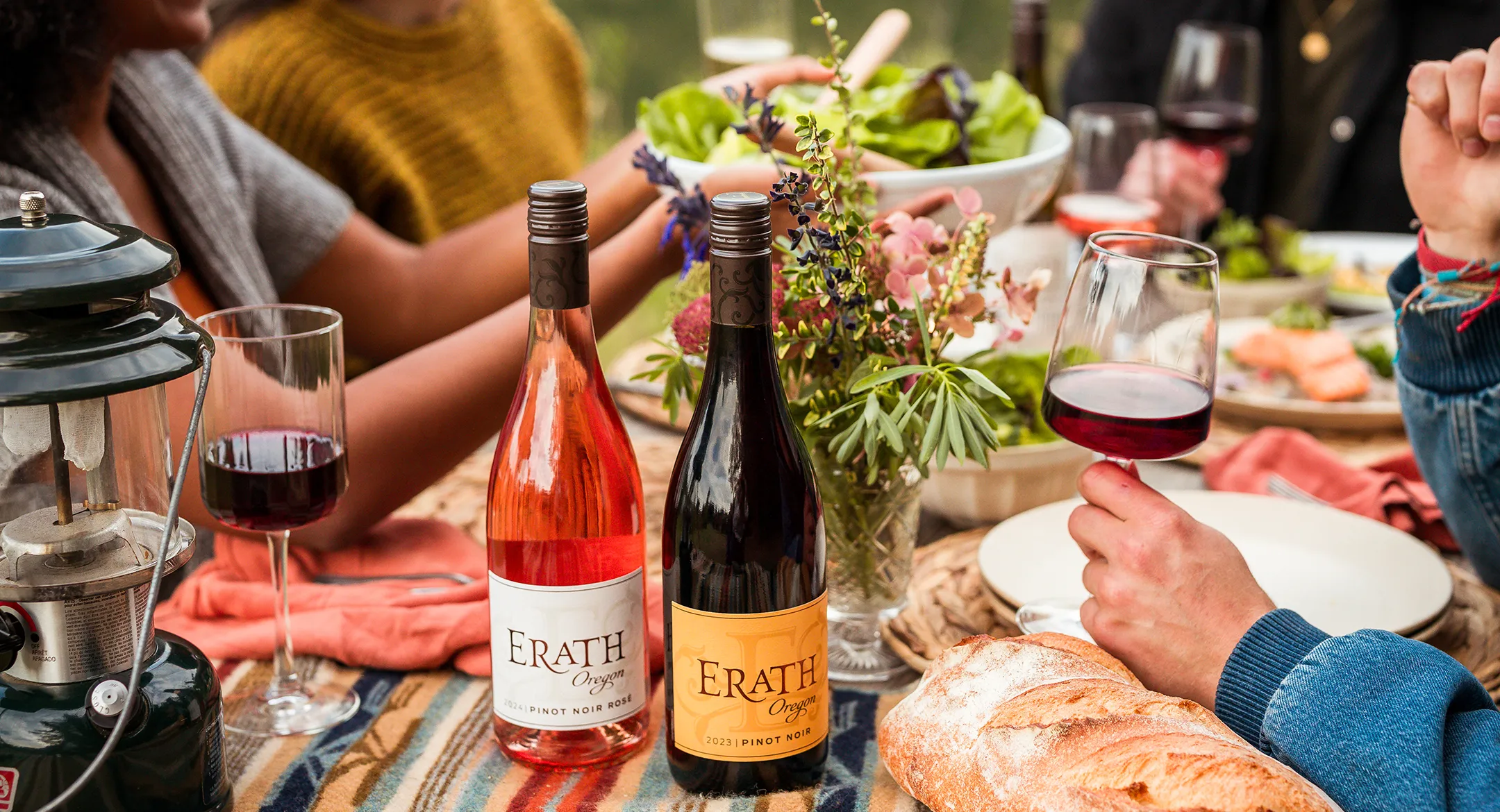 Friends gathered around a picnic table enjoying food and Erath wines.