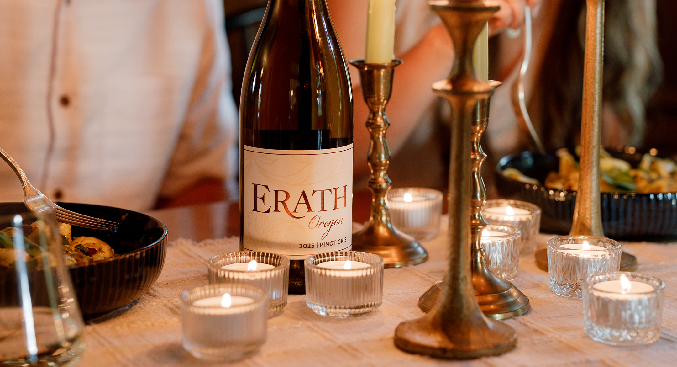People sitting a round a dinning table with candlelight and a bottle of Erath wine.